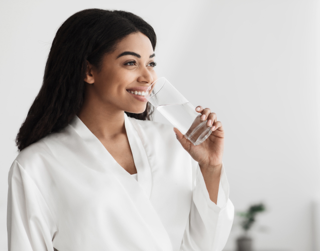 A photo of a smiling woman drinking water.