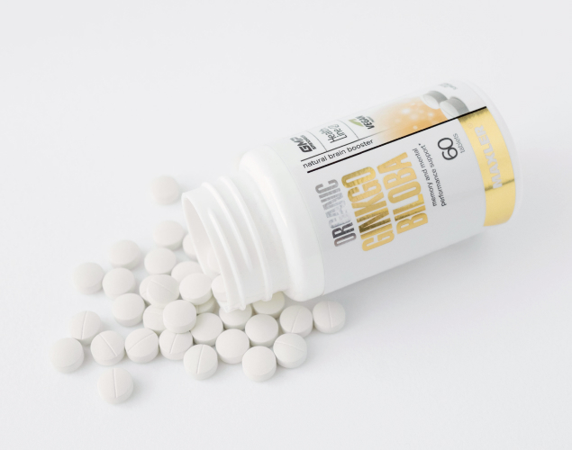 A picture of open Organic Ginkgo Biloba bottle with tablets laying near it.